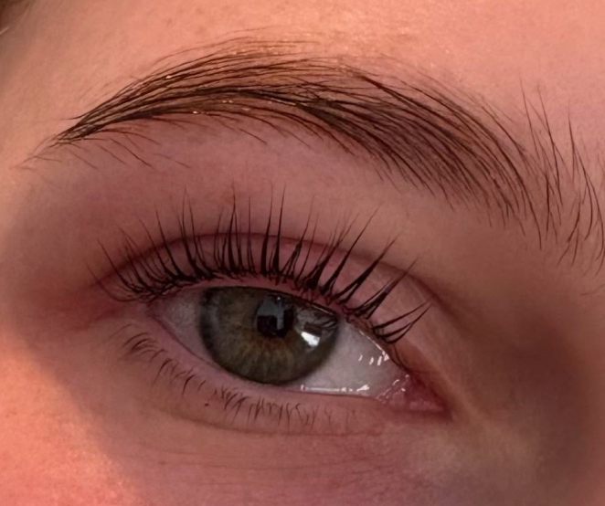 Close-up of an eye showing a lash lift with long, evenly lifted lashes and a neatly groomed eyebrow.