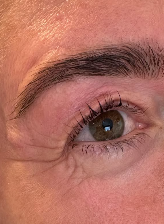 Close-up of an eye showing lifted, defined lashes and a neatly shaped, tinted eyebrow following a Korean lash lift, brow tint, and wax treatment.